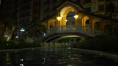 Evening outdoor pool with interiors. From under the bridge flow woman Stock Footage 91565715