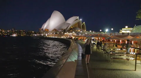 Evening pan from the opera house to the harbour bridge and woman posing Stock Footage 36699308