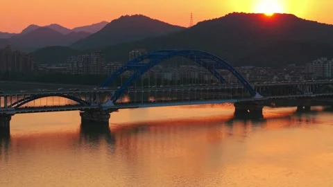 Evening panorama of a blue arch bridge with moving cars over calm water at Vídeo Stock 310118013