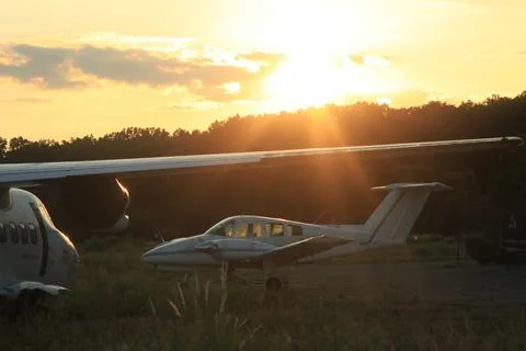 In the evening, planes are parked. The setting sun illuminates them from the Stock Photos