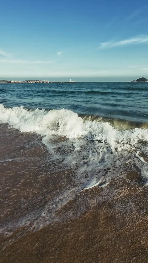 Evening Point of View follows long shadow cast on foamy waves and sand as camera Stock Footage 326364950