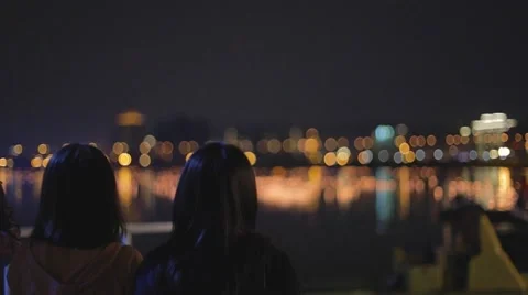 Evening - rack focus from two asian women to water lanterns Stock Footage 49405179