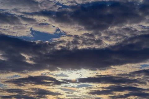 Evening rain clouds cover the setting sun. Stock Photos