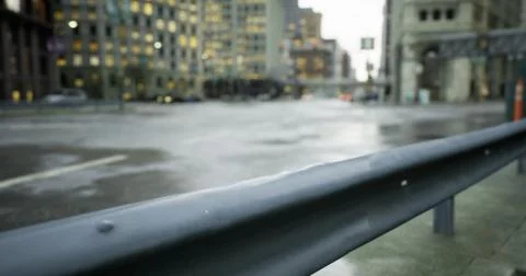 Evening rain creates reflections on city streets near tall buildings Ilustración de archivo
