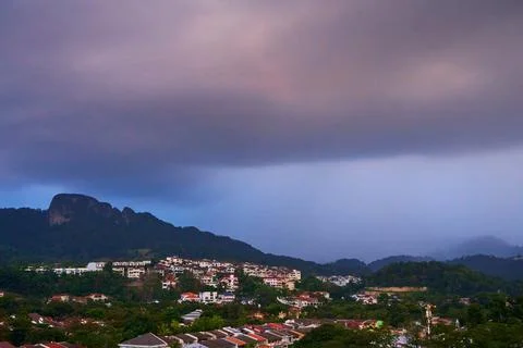 Evening rainy cloud bring rain to city under green hill Stock Photos