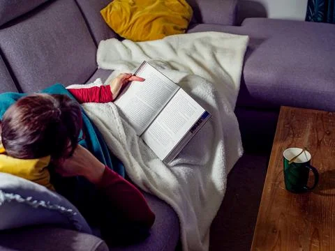 Evening reading with tea on a cozy sofa. Stock-Fotos