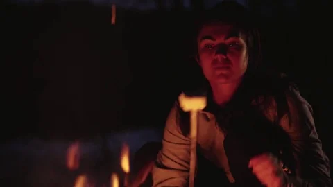Evening rest by the fire the girl eats marshmallow she is happy about taste Stock Footage 82503926
