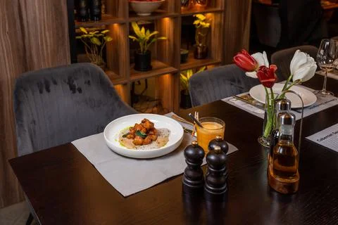 Evening restaurant dinner table with beef in sauce, juice and flowers Stock Photos