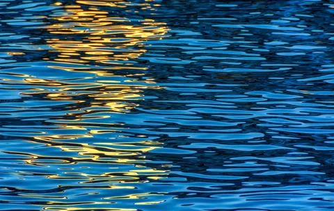 Evening river water texture with light reflection from a lantern. Stock Photos