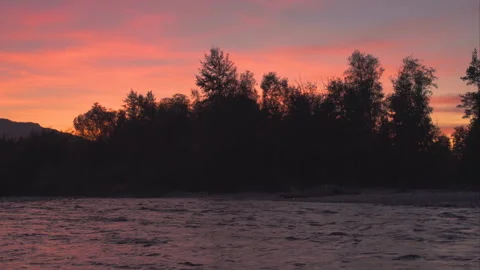 Evening scene at the river, silhouettes of trees at the rocky shore with su.. Stock Footage 252534605