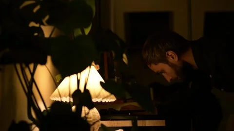 Evening scene with warm lamp light as a man bends over a vinyl record player 库存影片 330800663