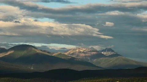 Evening scene of white, grey and bluish clouds billowing above a mountain Stock Footage 139349405