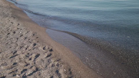 Evening seashore close up. Calm ocean water waves splashing sandy beach. Stockbeeldmateriaal 305293012