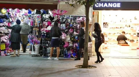 Evening Shoppers Browse Items on Display on Storefronts Stock Footage 57200453