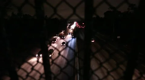 Evening shot of highway traffic from behind fence on a bridge Stock Footage 64798265