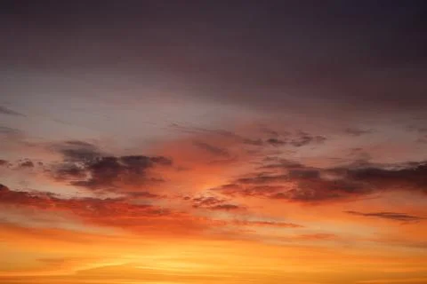 Evening sky ablaze with layered reds, oranges and golds as the setting sun Stock Photos