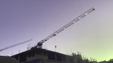 In the evening sky, a crane with burning bulbs on the boom against the Video stock 318444181