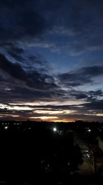 The evening sky features dark clouds with hints of orange and yellow sunset l Stock Photos