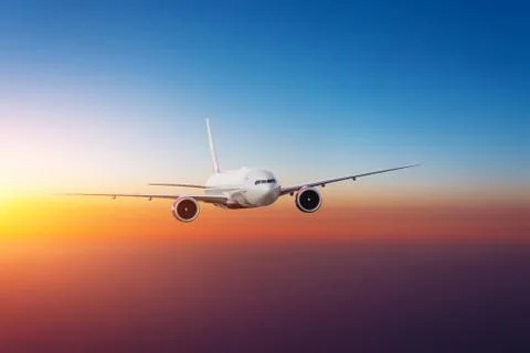 Evening sky gradient of warm colors and the airplane flies at flight level. 스톡 사진