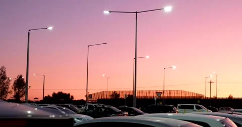 Evening sky with pink sunset over an urban road and a public outdoor car park Vídeo Stock 241795565
