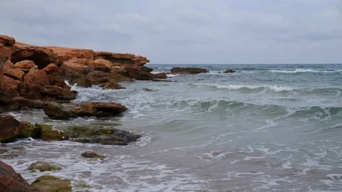 In the evening, small waves splash in slow motion on the rocks on the beach. Stock Footage 138208883