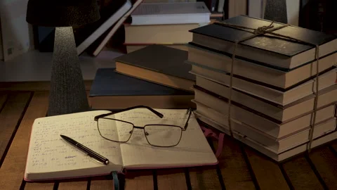 Evening study workspace with stacked books and notebook Stock Footage 336483717