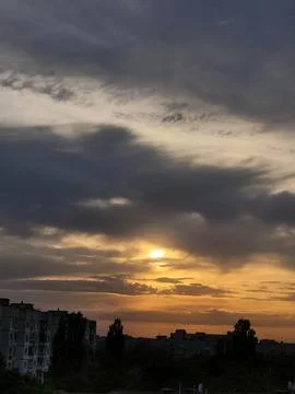 Evening sun glowing behind dark textured stratified cloud layer Stock Photos