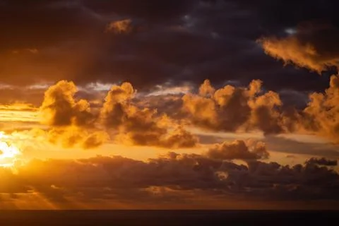 Evening sun hiding behind clouds Stock Photos