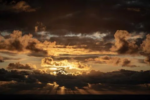 Evening sun hiding behind clouds Stock Photos