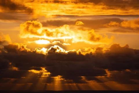 Evening sun hiding behind clouds Stock Photos
