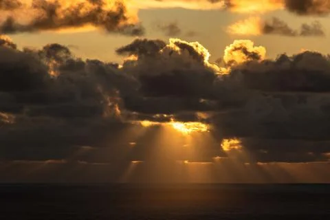 Evening sun hiding behind clouds Stock Photos