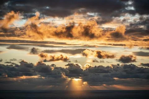 Evening sun hiding behind clouds Stock Photos