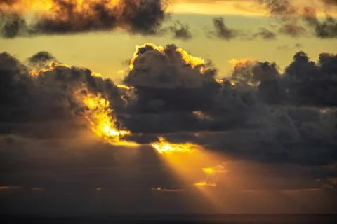 Evening sun hiding behind clouds Stock Photos