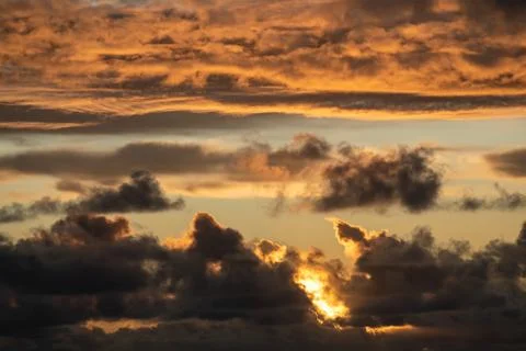 Evening sun hiding behind clouds Stock Photos