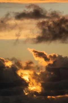 Evening sun hiding behind clouds Stock Photos