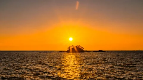 The evening sun is over a small reef above the sea. Zoom out Stock Footage 145702310