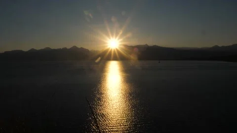 An evening sun setting behind the mountain and reflecting in the sea water Stock Footage 311156526