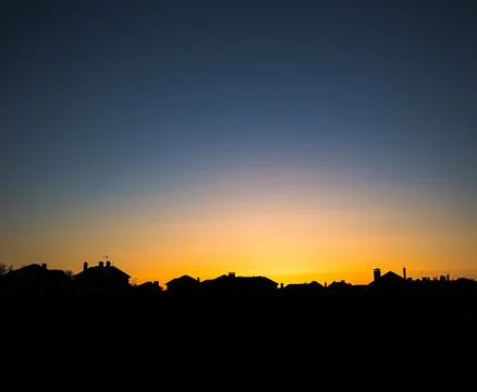 Evening sun setting behind a row of suburban houses Foto stock