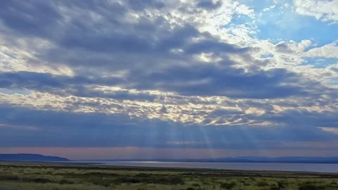 The evening sun shines through the clouds, illuminating the lake Stock Footage 317386448