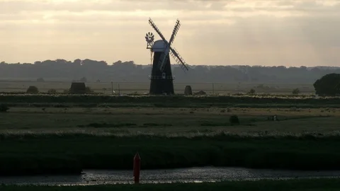 Evening Sun shining through the clouds a Windmill on The Broads National Park Stock Footage 91791578