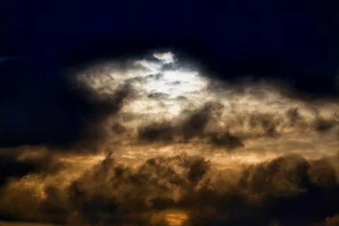 Evening sunlight breaks through dark clouds, gloomy light in the sky Stock Photos