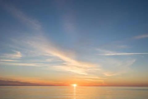 Evening sunlight on coast, pink clouds, blue sky reflection on water. Beach i Foto stock
