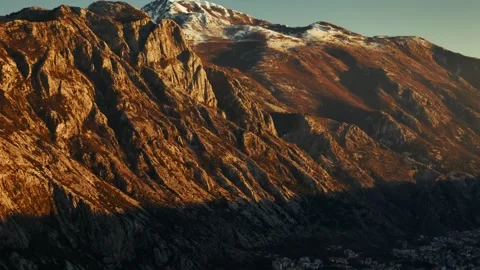 Evening sunlight illuminates mountains at Kotor Bay revealing a coastal town Stock Footage 313733459