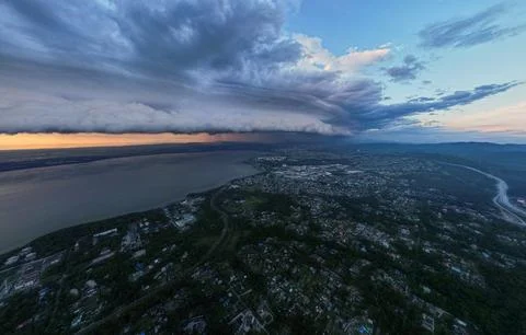 Evening sunset with powerful dark clouds over the sea city, stormy weather, foo Stock Photos