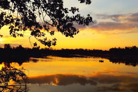 Evening, sunset, river, reflection of clouds in the water, boat with fisherma Stock Photos