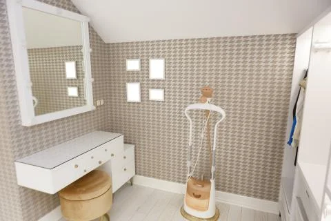 An evening table with a ottoman and a square mirror on the wall. Stock Photos