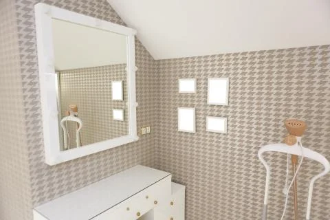 An evening table with a ottoman and a square mirror on the wall. Stock Photos