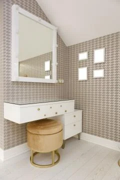 An evening table with a ottoman and a square mirror on the wall. Stock Photos