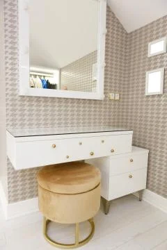 An evening table with a ottoman and a square mirror on the wall. Stock Photos