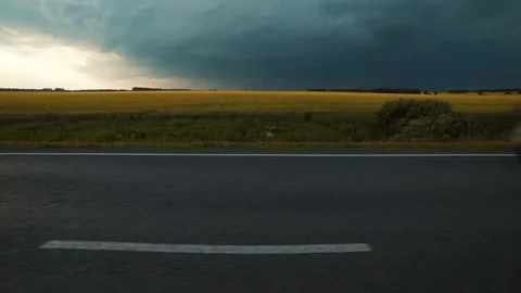 Evening, thunder over the farm field. The camera is moving along the road. At Stock Footage 78224878